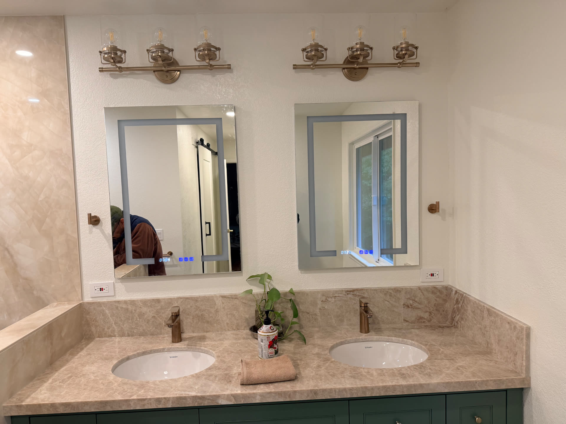 Green shaker double vanity with stone counter, LED mirrors and bronze sconces