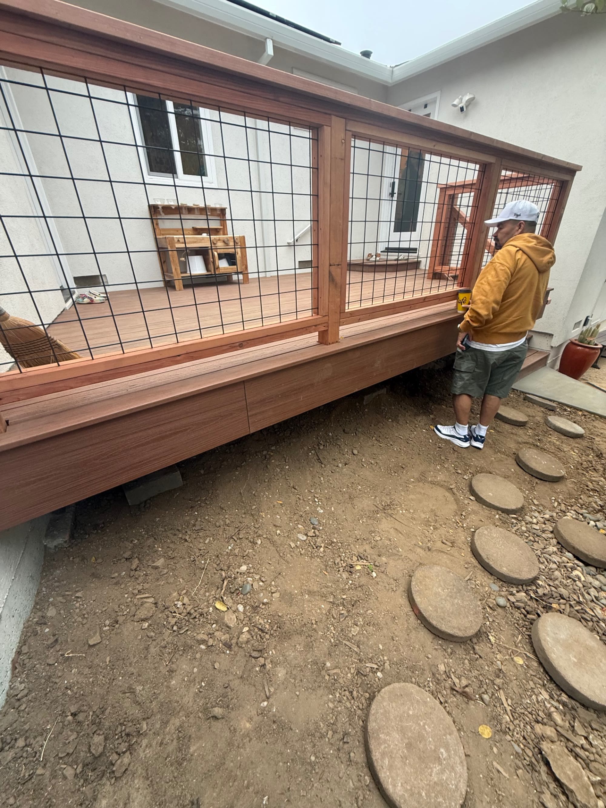 Side run of the deck with redwood posts and black wire mesh railing panels