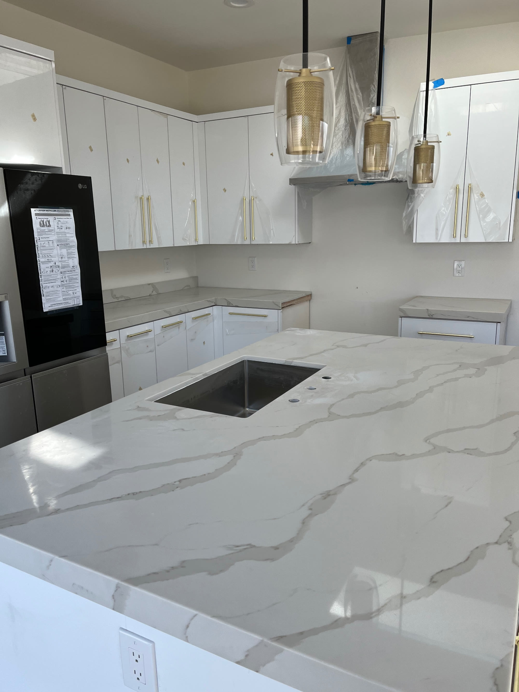 Quartz island with undermount sink and gold glass pendants overhead