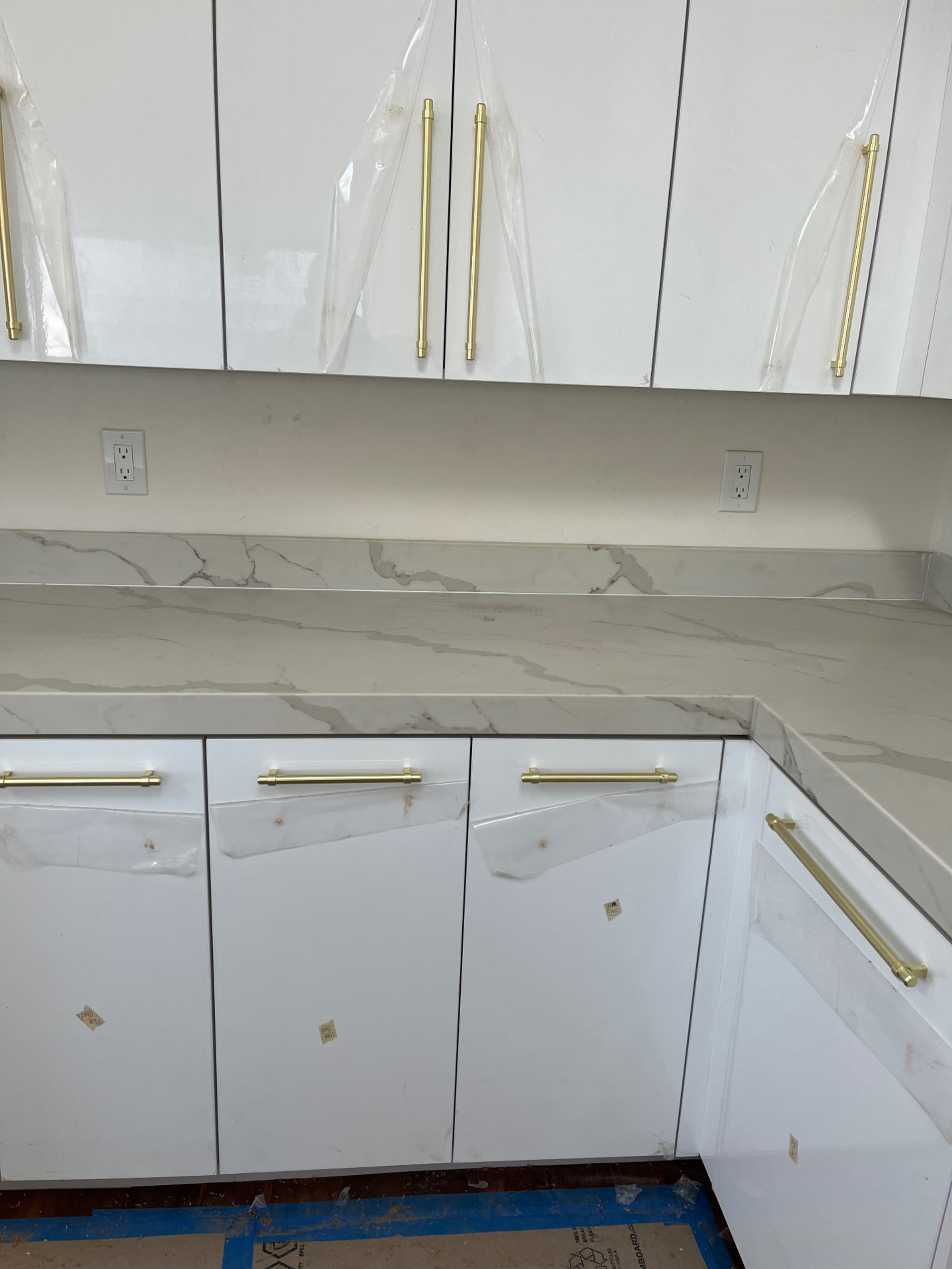 Detail of white gloss cabinets, quartz backsplash and brushed gold hardware