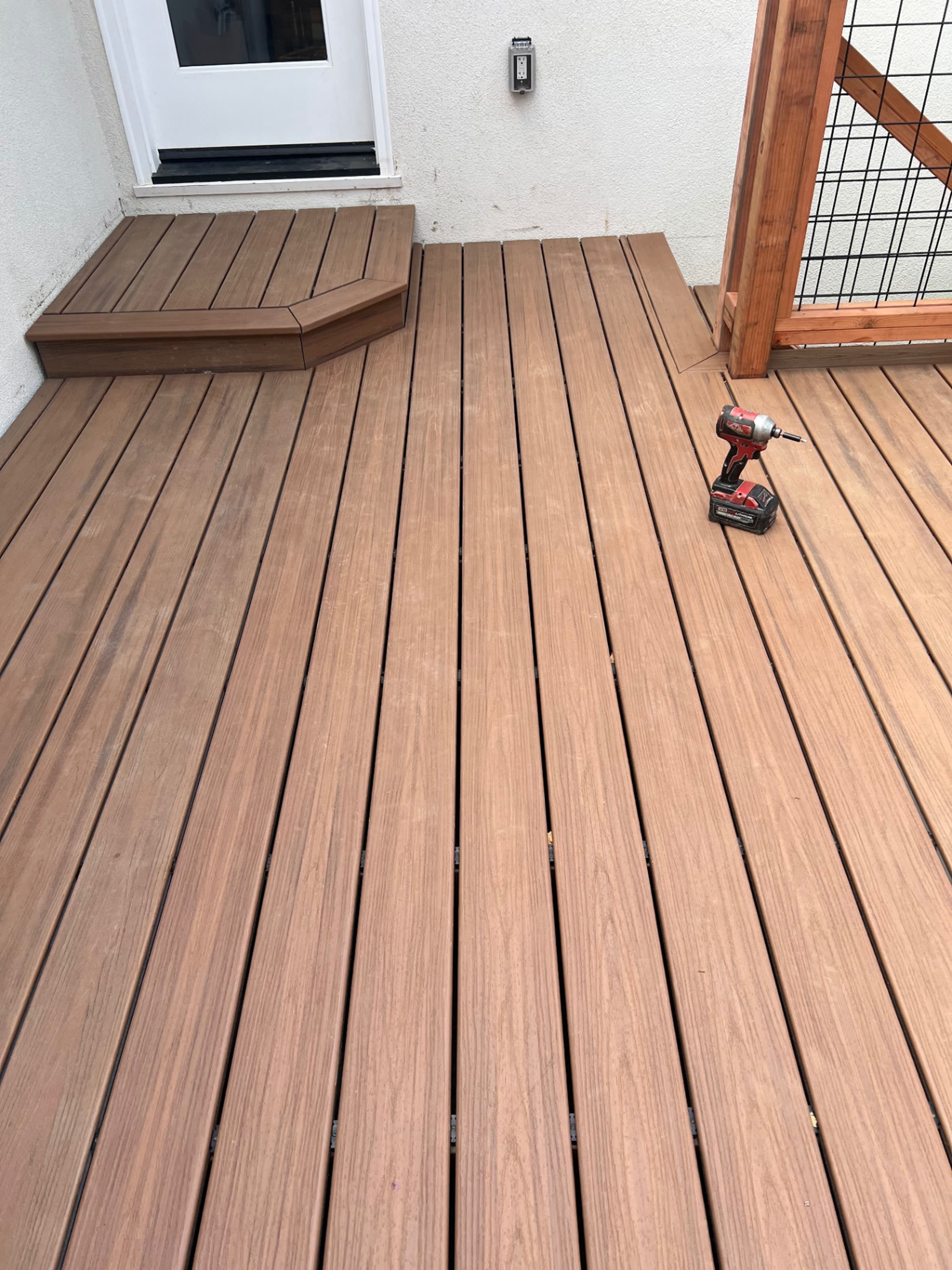 Warm brown composite decking with a landing step at the back door