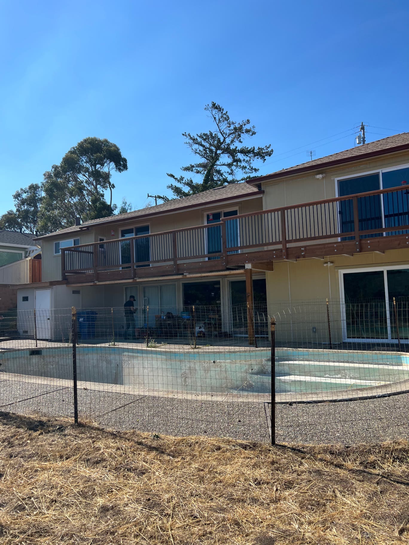 Redwood deck and railing running along the rear elevation above the pool deck