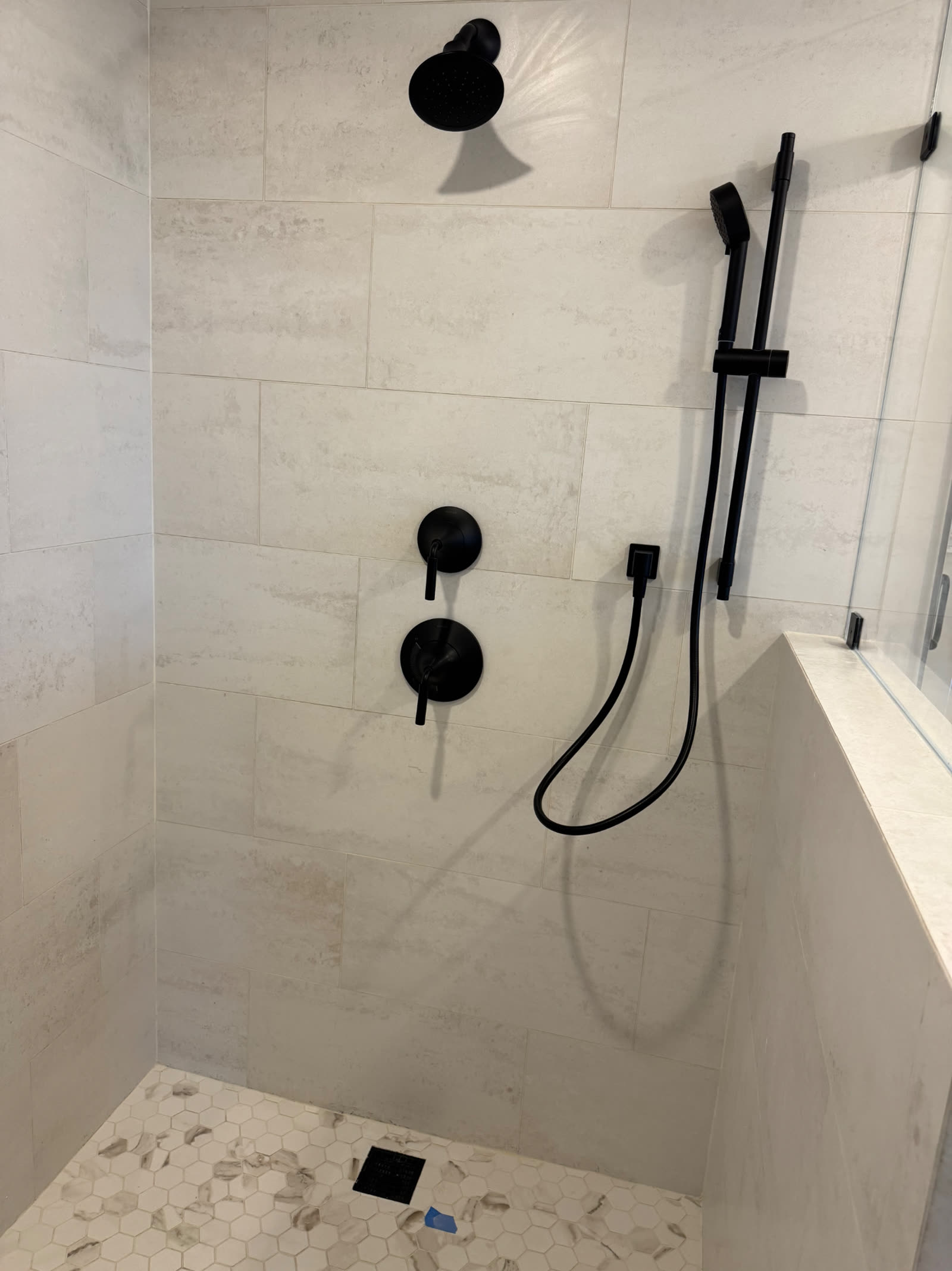 Walk-in shower with large-format tile, rain head and marble hex floor