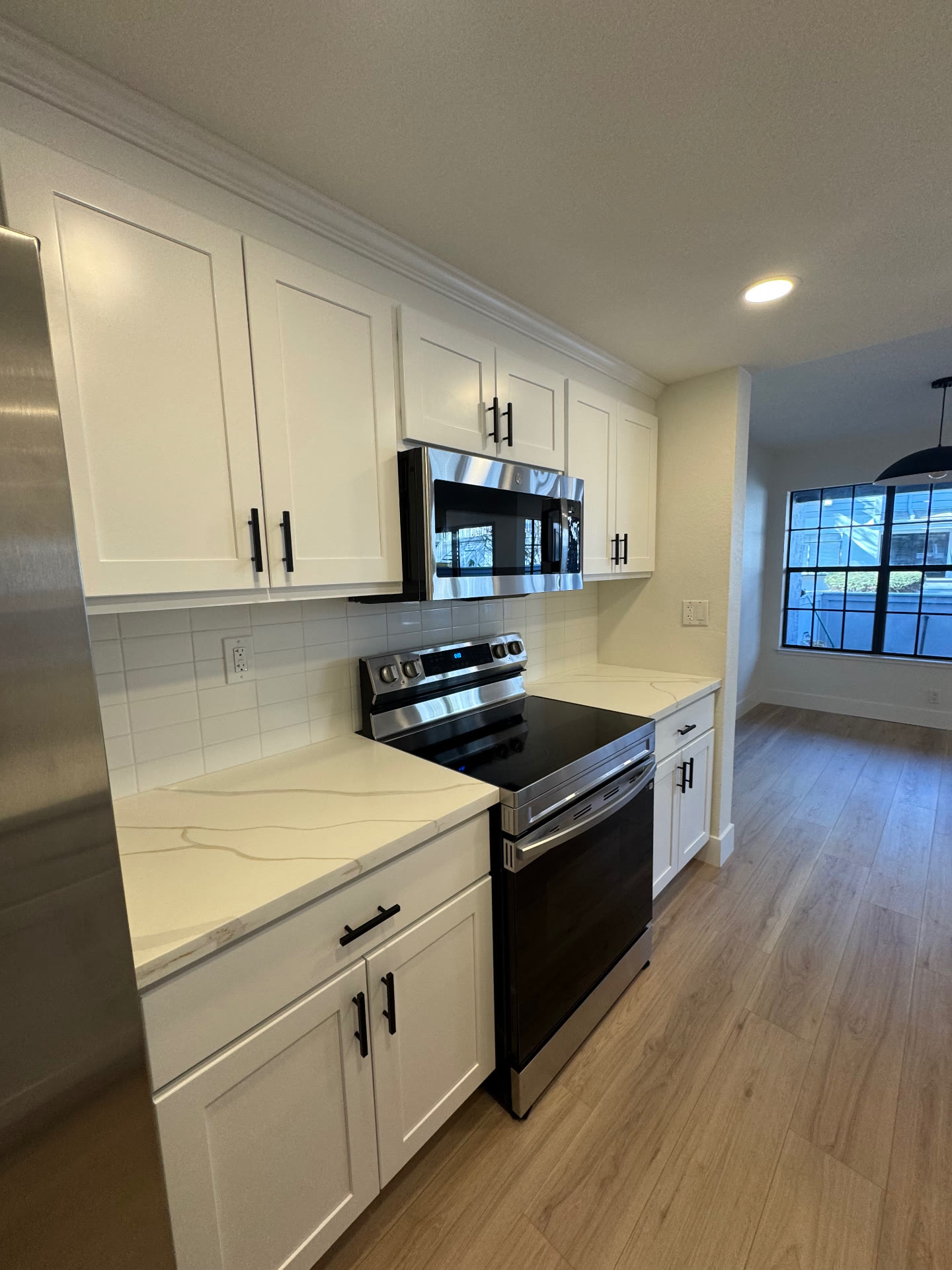 Range wall with stainless appliances, white tile backsplash and matte black hardware