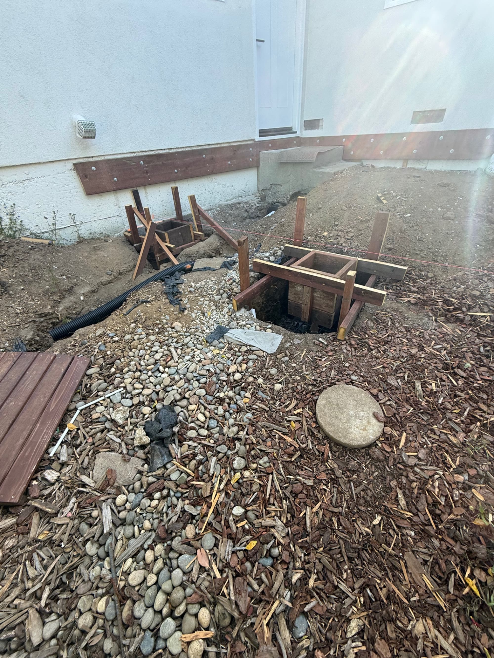 Side yard during construction, with formed concrete footings in place along the foundation