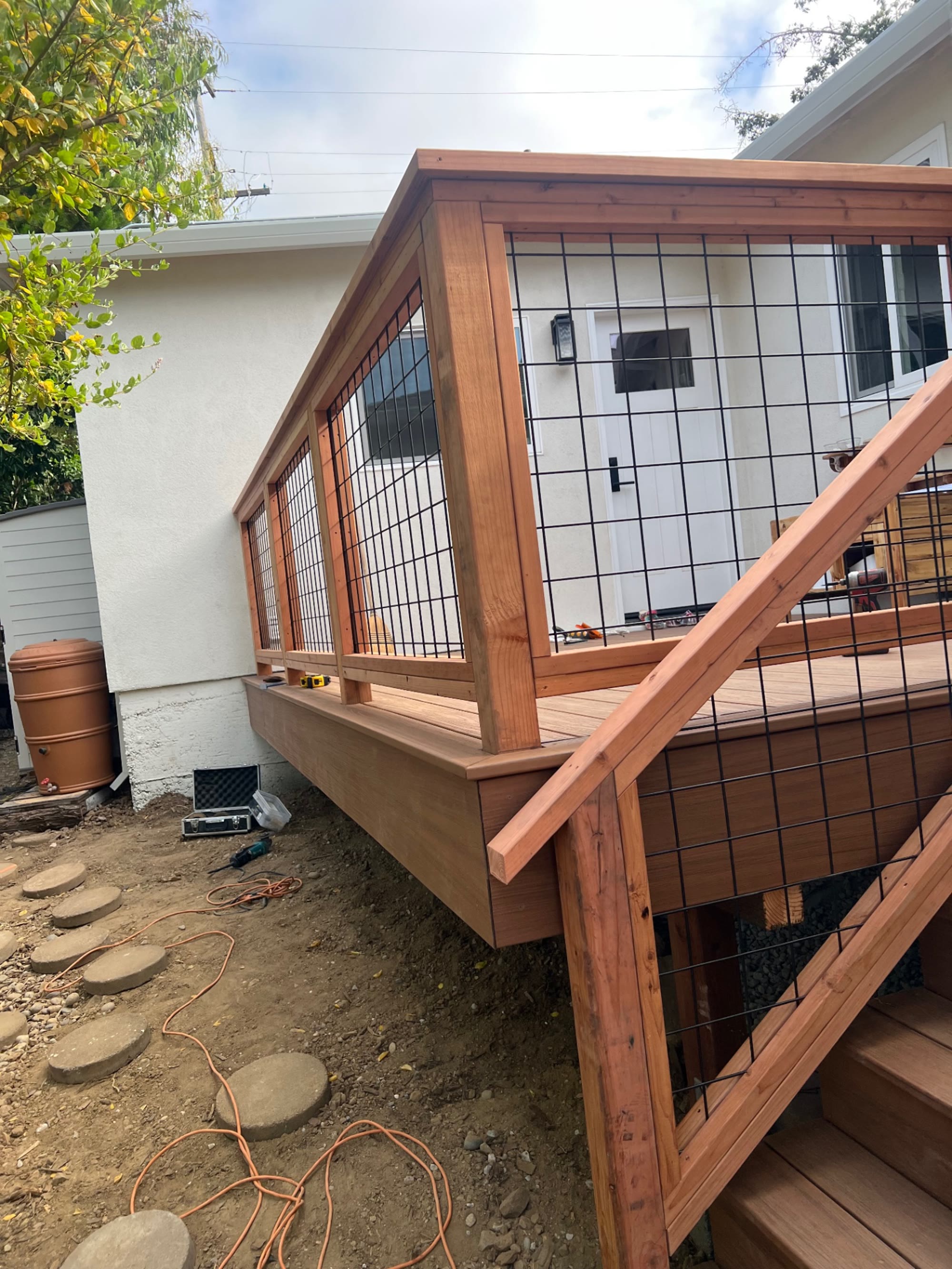 Composite deck with redwood and wire mesh railing wrapping the corner of a Belmont home