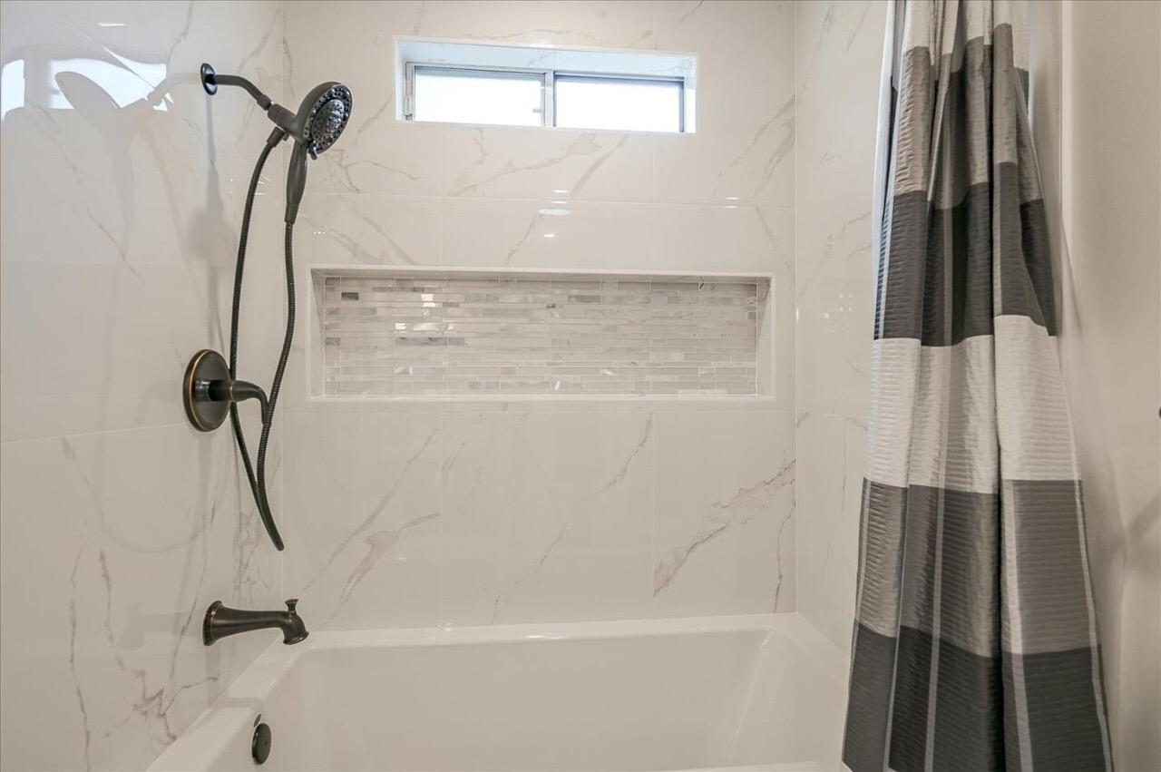 Tub and shower surround in marble-look porcelain with a recessed mosaic niche