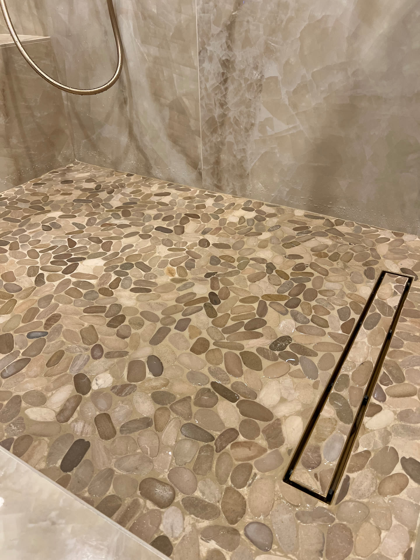 Close view of the pebble shower floor and linear drain