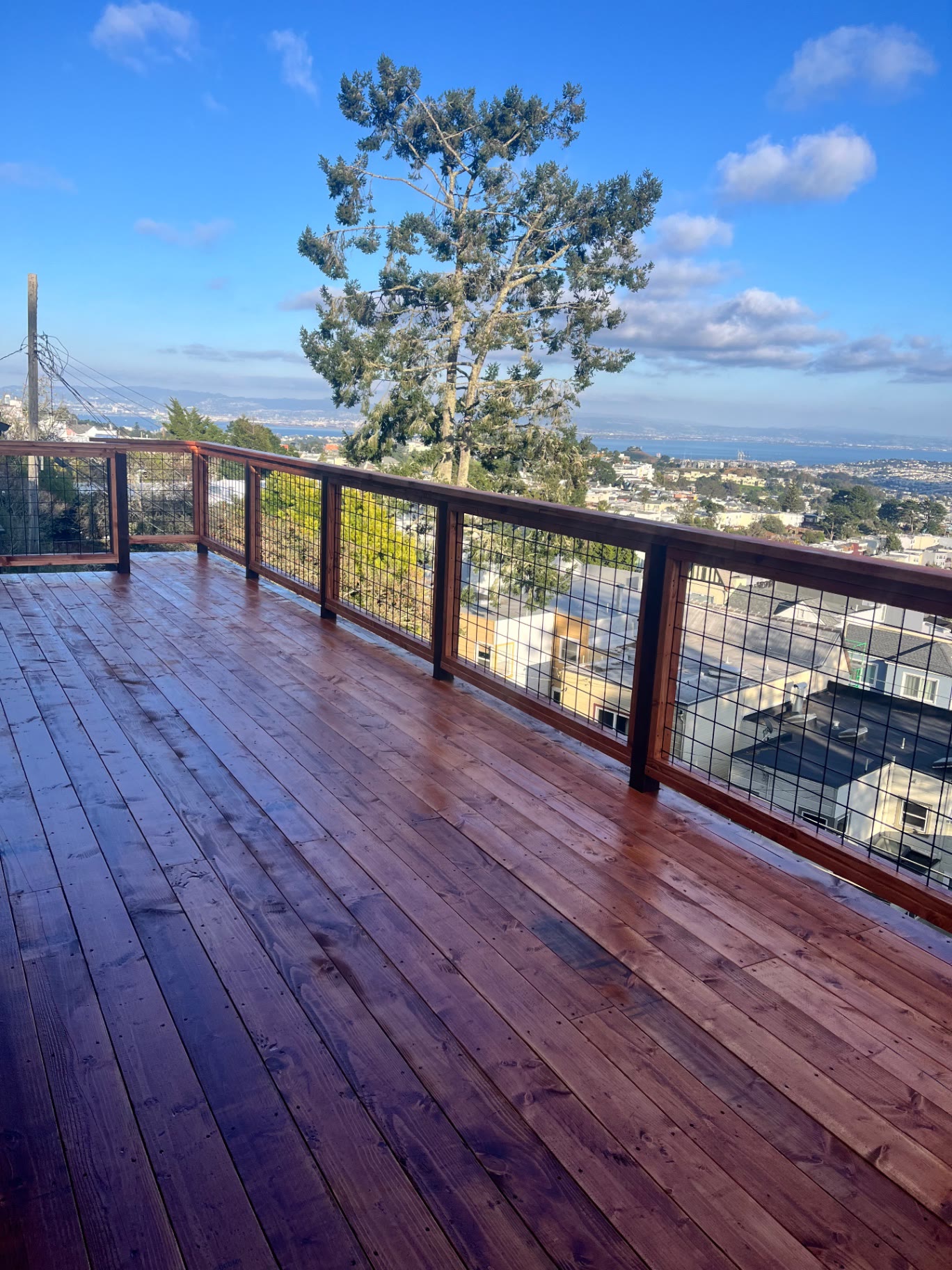 Redwood deck with wire panel railing and a view over the city rooftops