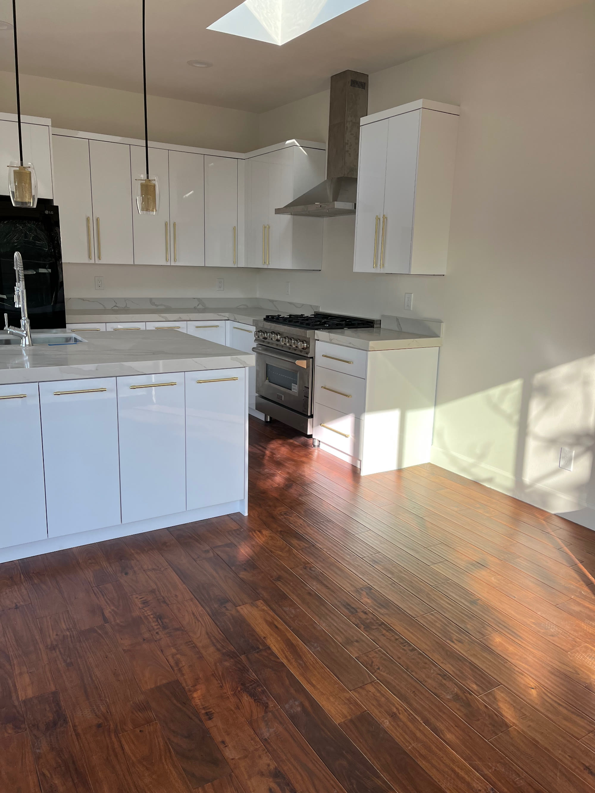 Range wall with gas range, chimney hood and hardwood flooring
