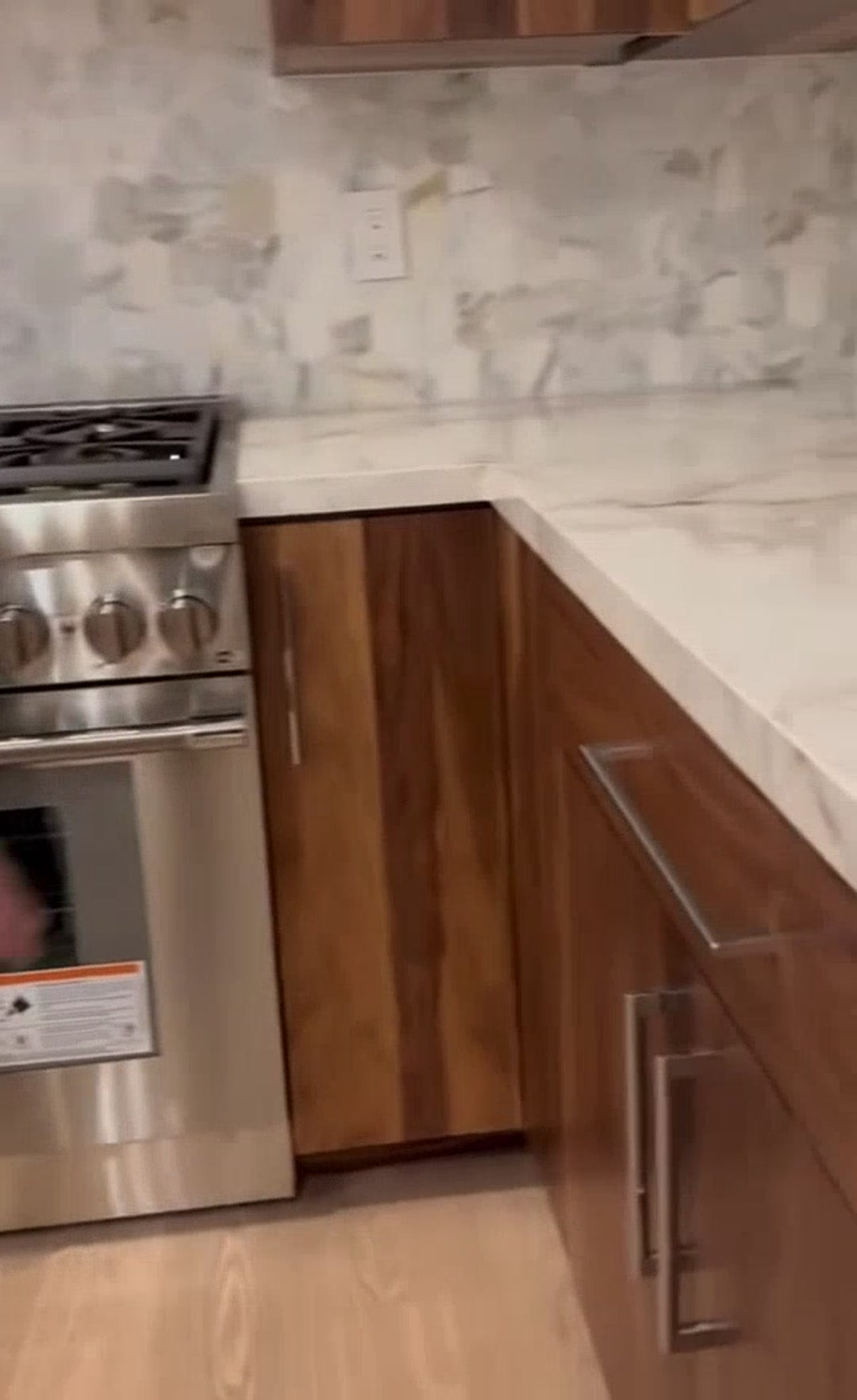 Remodeled kitchen with walnut cabinetry, marble backsplash and a stainless range